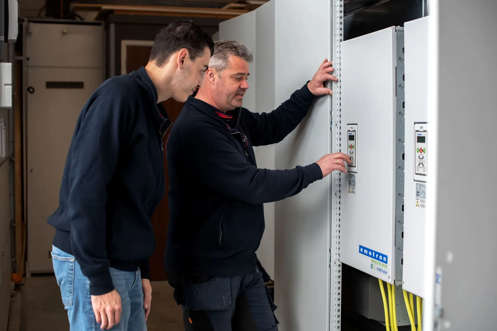 Engineers bij een grote besturingskast in de werkplaats