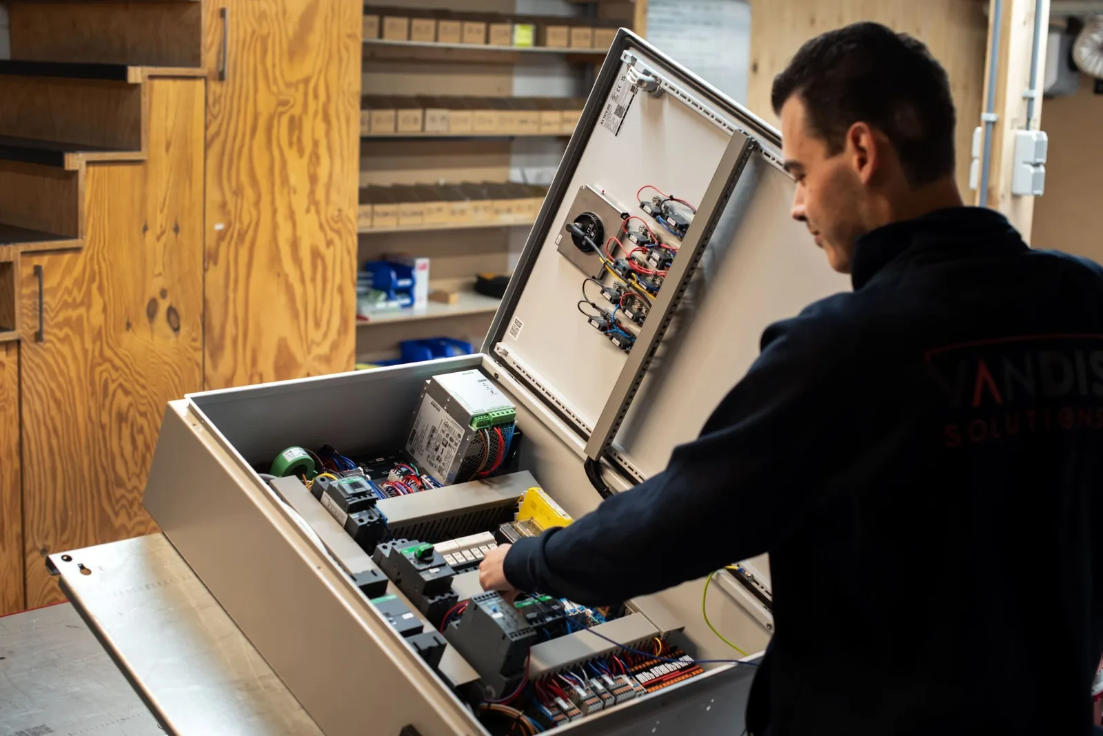 Monteur bedraadt een besturingskast in de werkplaats van Van Dis Solutions