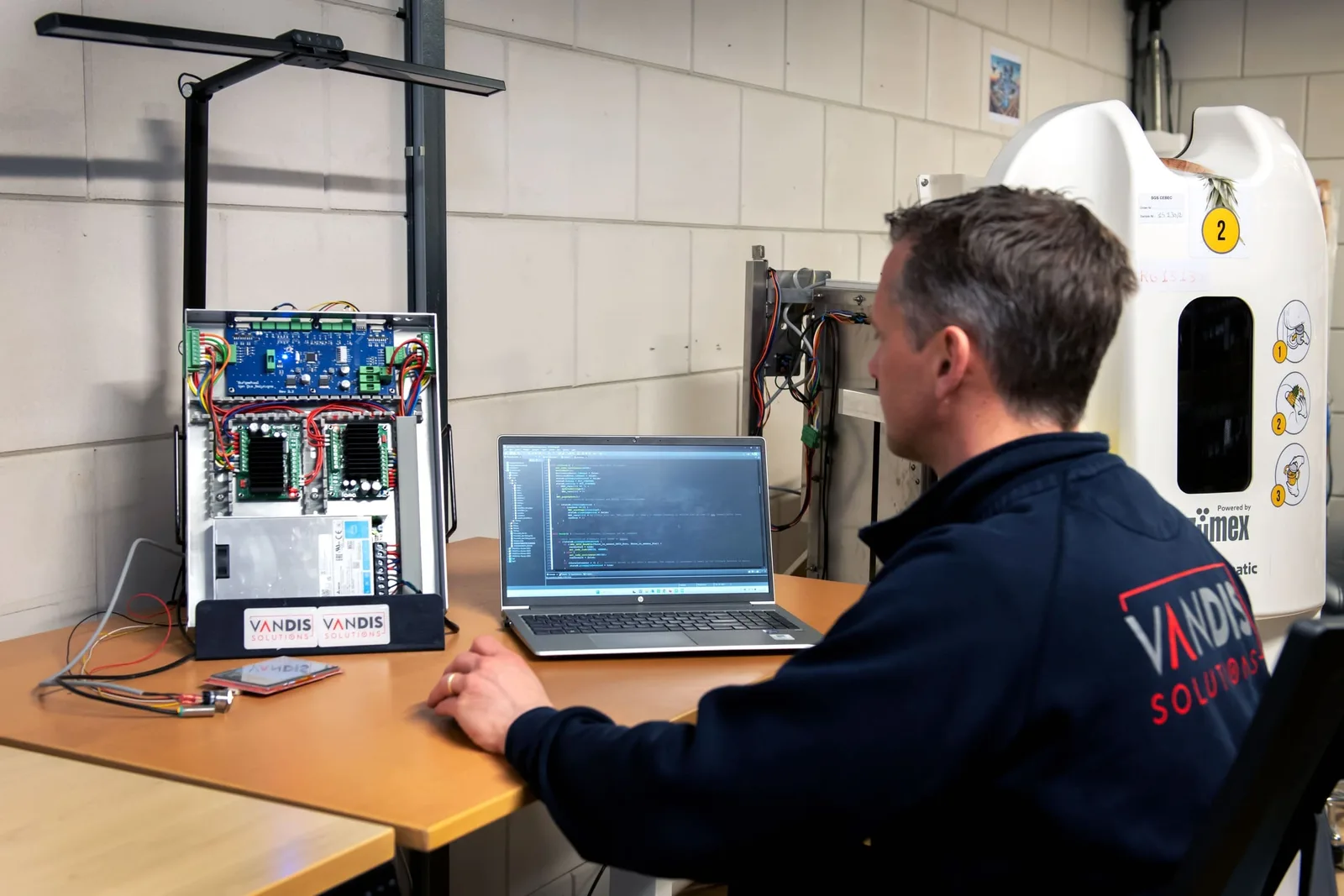 Software engineer ontwikkelt besturingssoftware naast een testopstelling