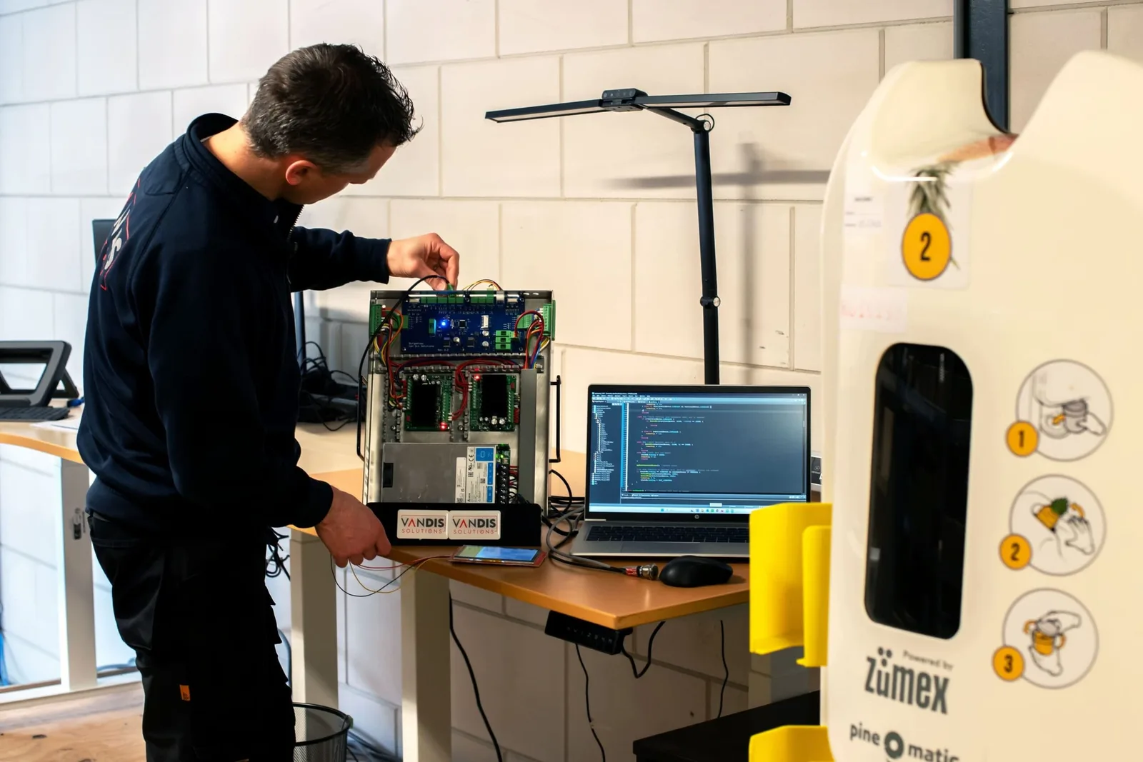 Engineer test besturingssoftware met laptop op een testopstelling
